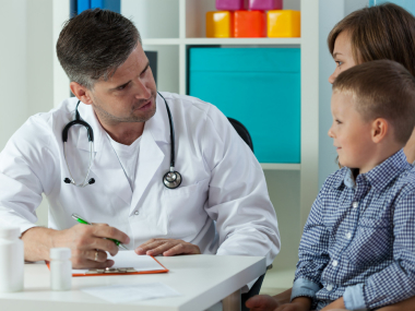 A doctor examining a young boy with Prader-Willi Syndome